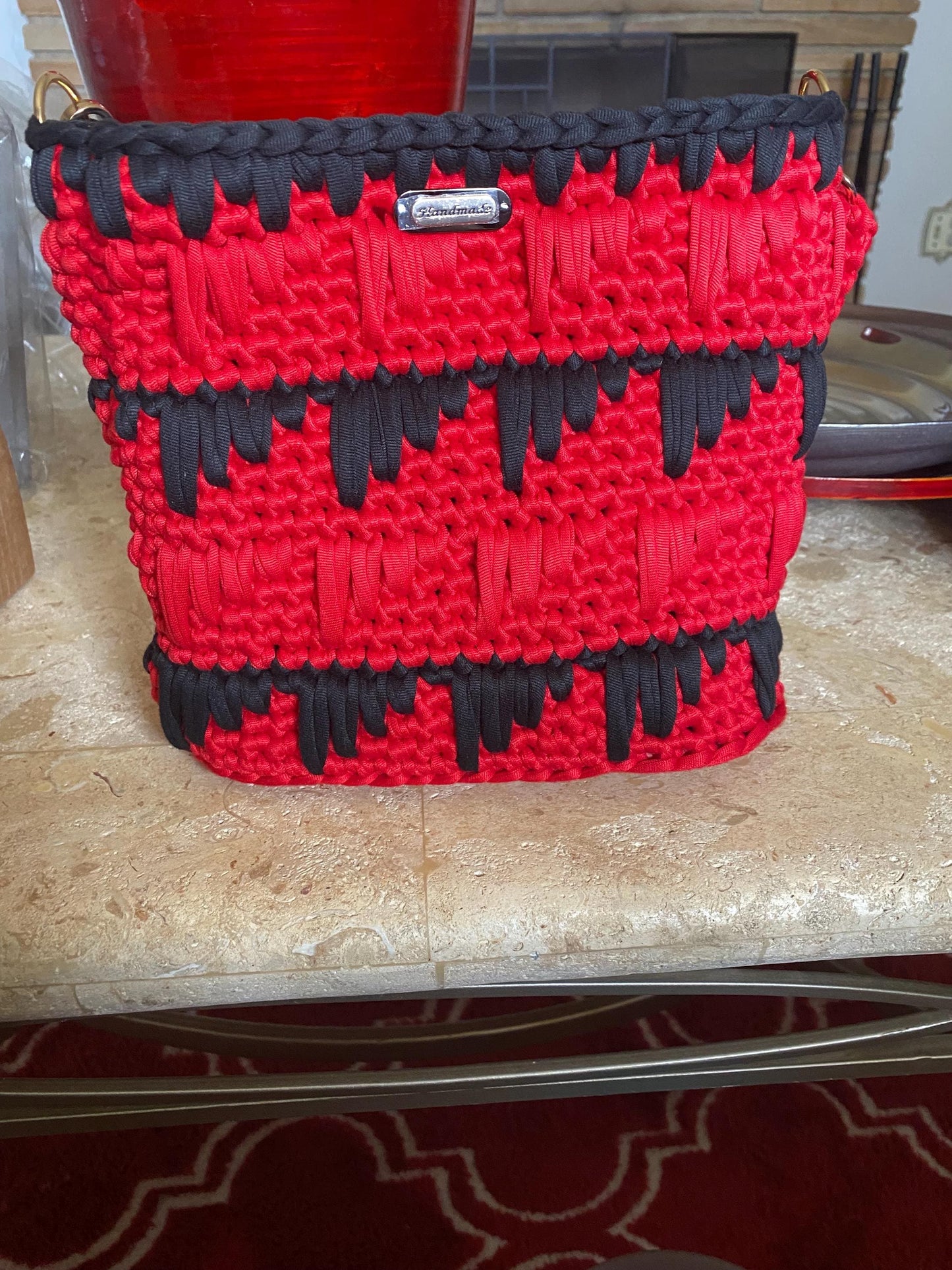 Black and red crocheted purse with leather bottom.